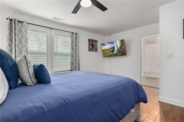 bedroom featuring ceiling fan, connected bathroom, and dark hardwood / wood-style floors