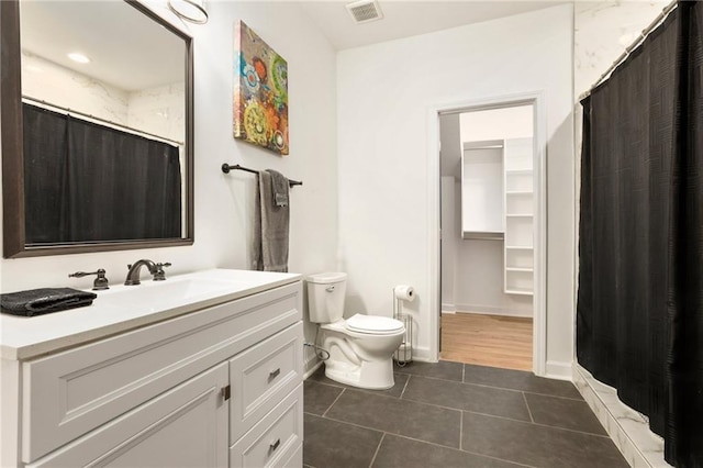 bathroom with toilet, vanity, walk in shower, and tile patterned flooring