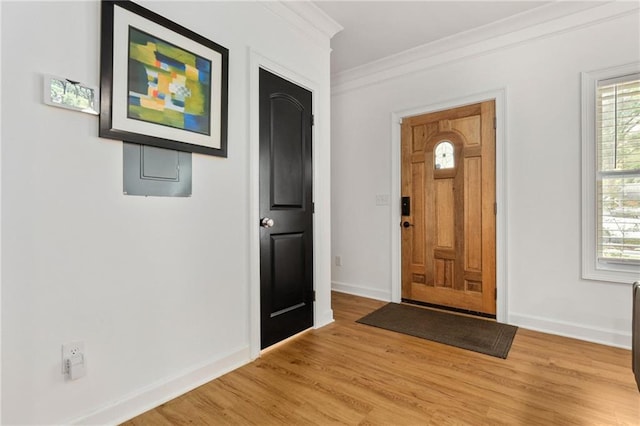 foyer entrance with crown molding and light hardwood / wood-style floors