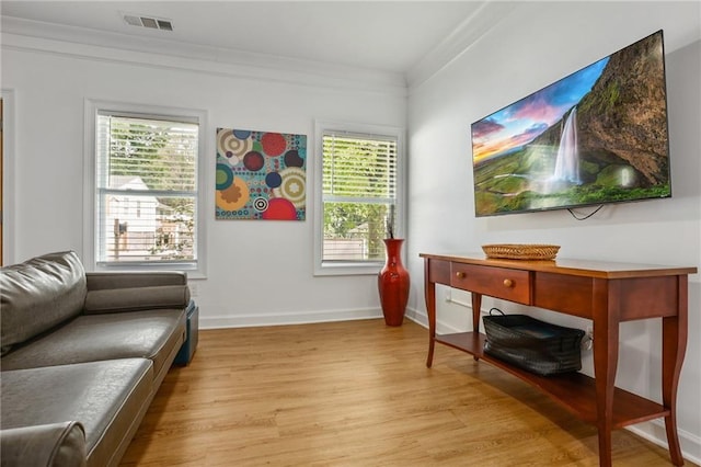 sitting room featuring light wood-type flooring, a wealth of natural light, and crown molding