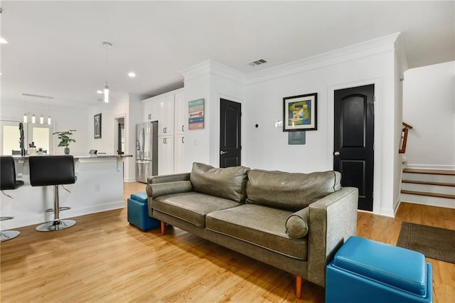 living room with light wood-type flooring and crown molding