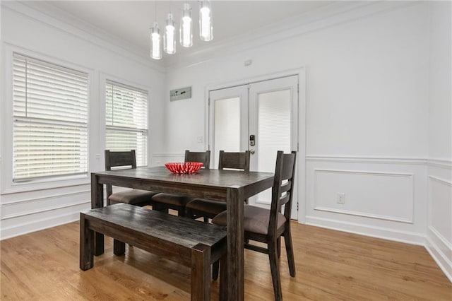 dining area with crown molding, an inviting chandelier, and light hardwood / wood-style flooring