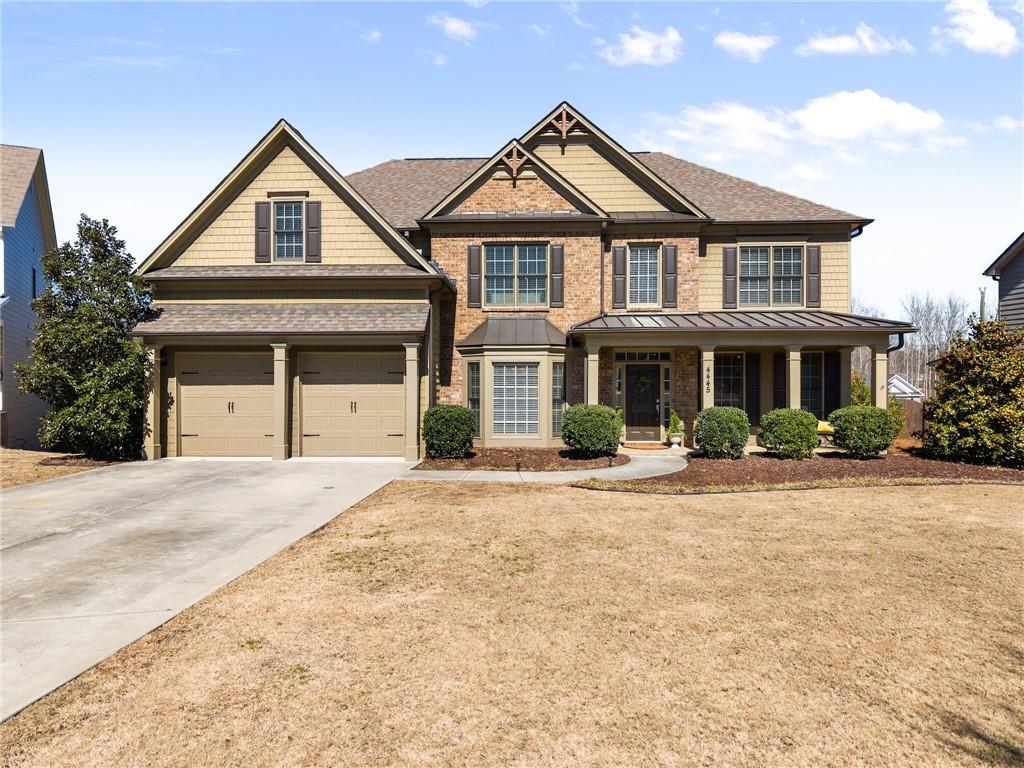 craftsman house featuring driveway, a standing seam roof, a porch, and a front yard