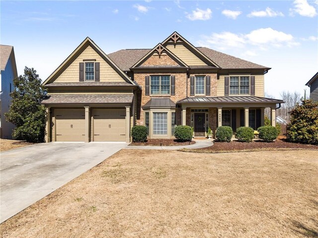 craftsman house featuring driveway, a standing seam roof, a porch, and a front yard