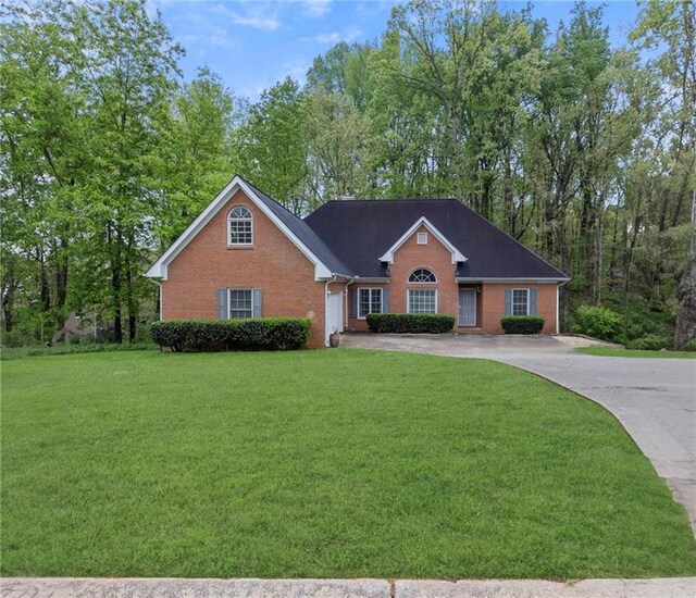 view of front of house featuring a front yard, a garage, brick siding, and driveway