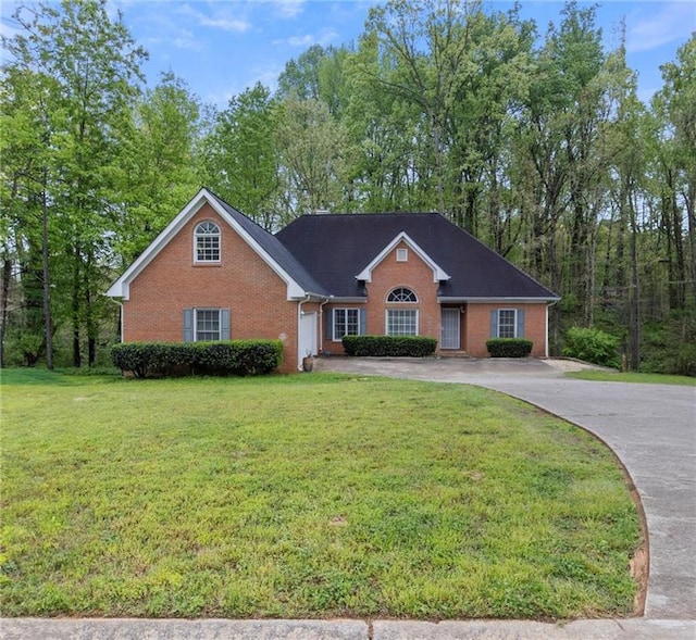 view of front of home featuring driveway, brick siding, an attached garage, and a front yard
