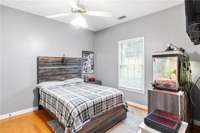 bedroom featuring visible vents, baseboards, wood finished floors, and a ceiling fan