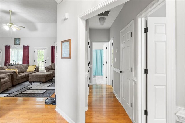 hall featuring visible vents, baseboards, and light wood-style flooring