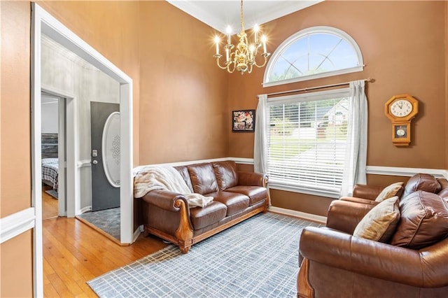 living area featuring hardwood / wood-style flooring, baseboards, a towering ceiling, and a chandelier