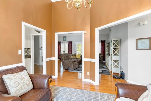 interior space with a high ceiling, wood finished floors, baseboards, and a chandelier