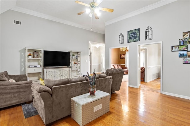 living room with light wood-type flooring, visible vents, a ceiling fan, and crown molding