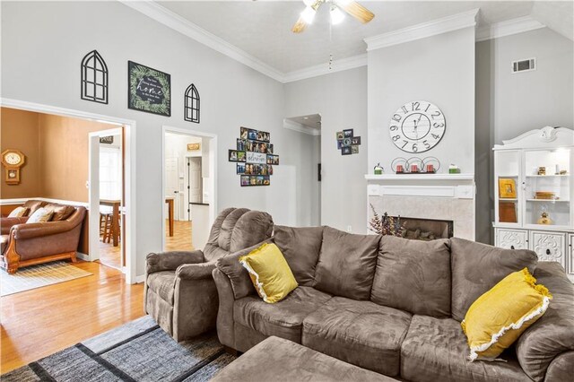 living room featuring wood finished floors, a ceiling fan, visible vents, and ornamental molding
