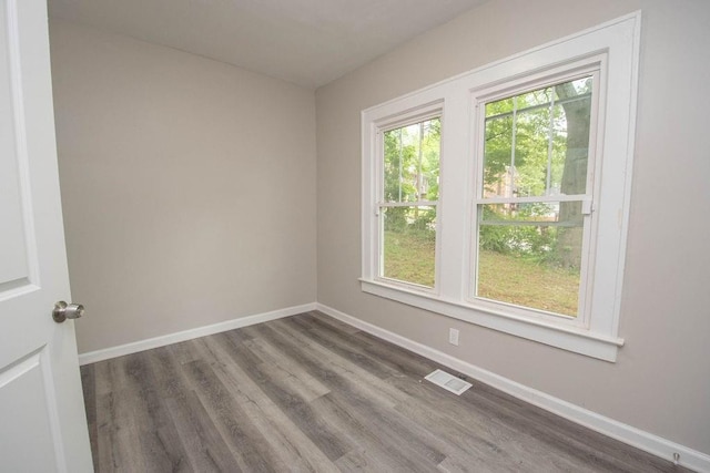 spare room with baseboards, visible vents, and wood finished floors