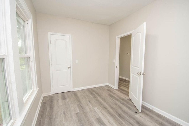 unfurnished room with light wood-type flooring and baseboards