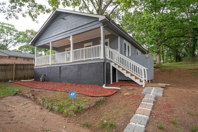 view of front of house featuring stairs, covered porch, and fence