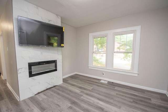 unfurnished living room featuring visible vents, wood finished floors, baseboards, and a premium fireplace