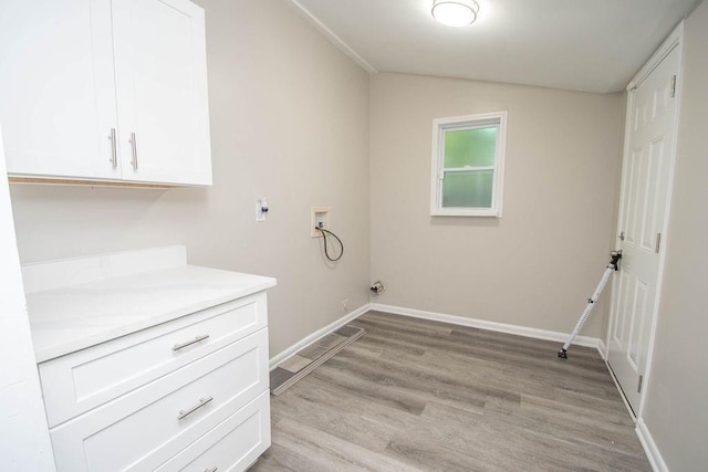 washroom with baseboards, hookup for a washing machine, cabinet space, and light wood-style floors