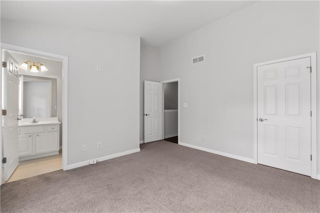 unfurnished bedroom featuring sink, high vaulted ceiling, ensuite bath, and carpet flooring