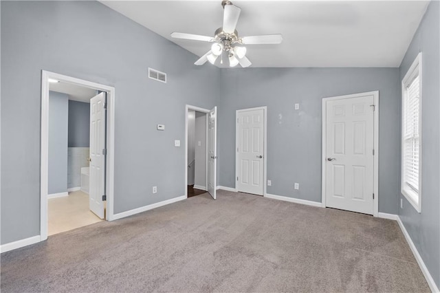 unfurnished bedroom with vaulted ceiling, ensuite bath, ceiling fan, and light carpet