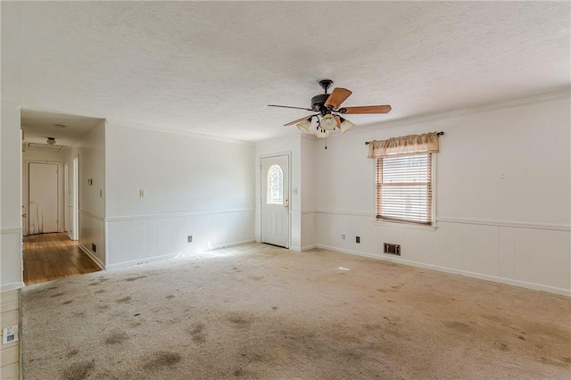 empty room with ceiling fan, crown molding, light colored carpet, and a textured ceiling