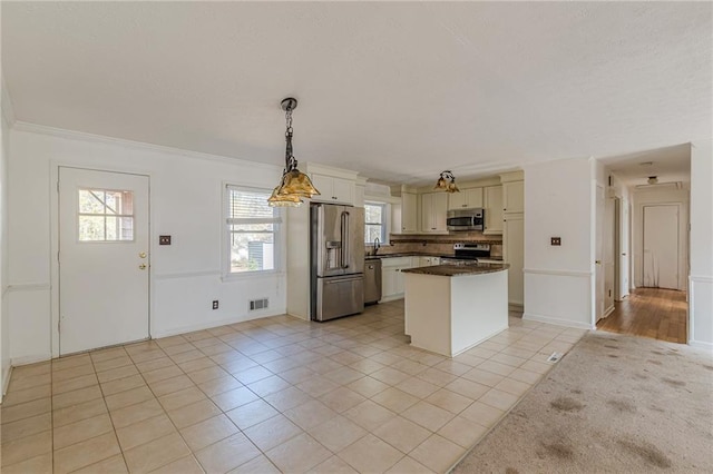 kitchen featuring pendant lighting, sink, ornamental molding, light tile patterned floors, and stainless steel appliances