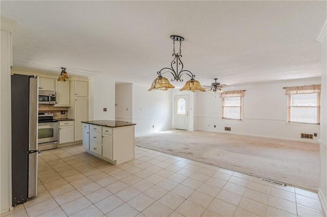 kitchen featuring appliances with stainless steel finishes, pendant lighting, a center island, ceiling fan, and light carpet