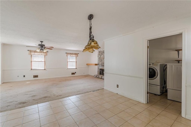 interior space with a fireplace, separate washer and dryer, ceiling fan, crown molding, and light carpet