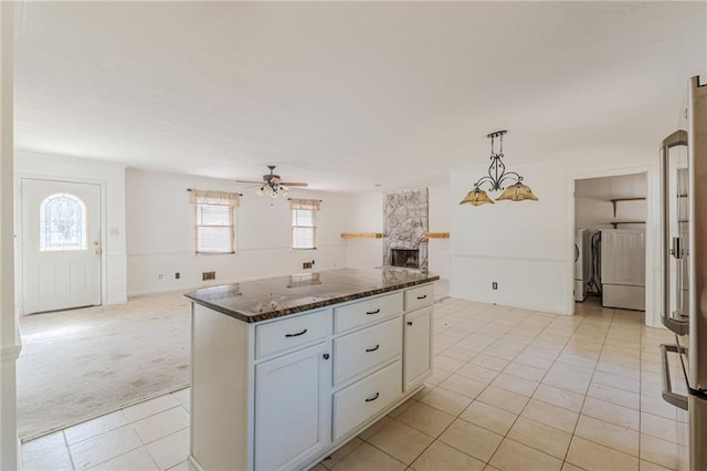 kitchen with light carpet, dark stone countertops, pendant lighting, independent washer and dryer, and white cabinets