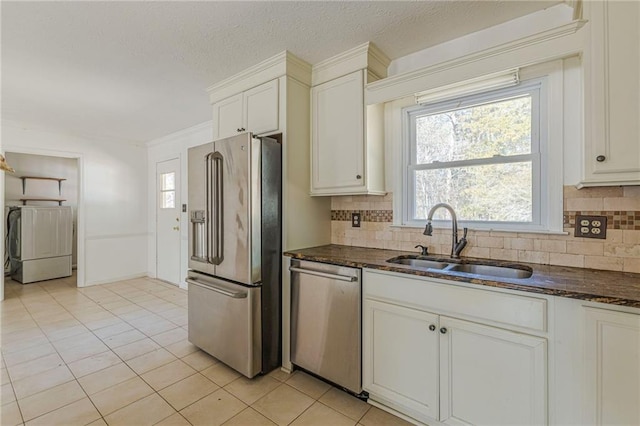 kitchen featuring sink, white cabinetry, backsplash, stainless steel appliances, and washer / clothes dryer