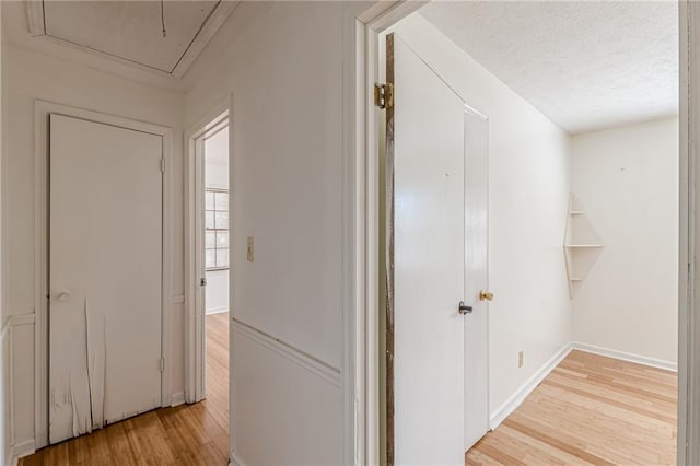 hall with a textured ceiling and light wood-type flooring