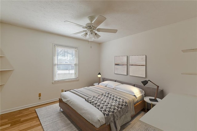 bedroom with ceiling fan, light hardwood / wood-style flooring, and a textured ceiling