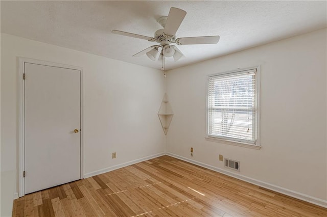 spare room with ceiling fan, light hardwood / wood-style flooring, and a textured ceiling