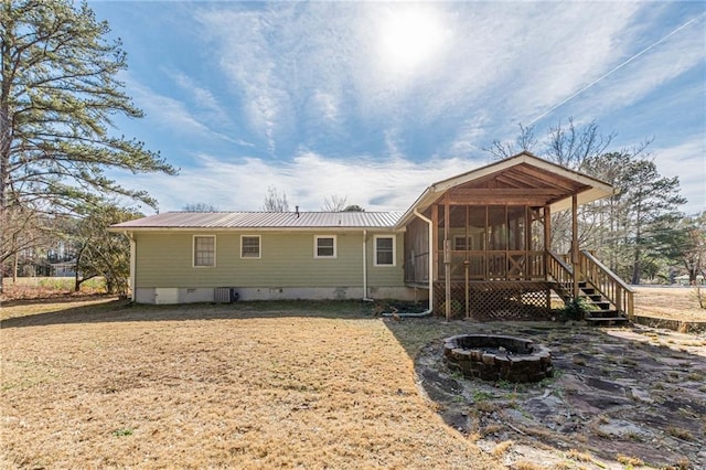 rear view of property featuring cooling unit, a sunroom, and a fire pit