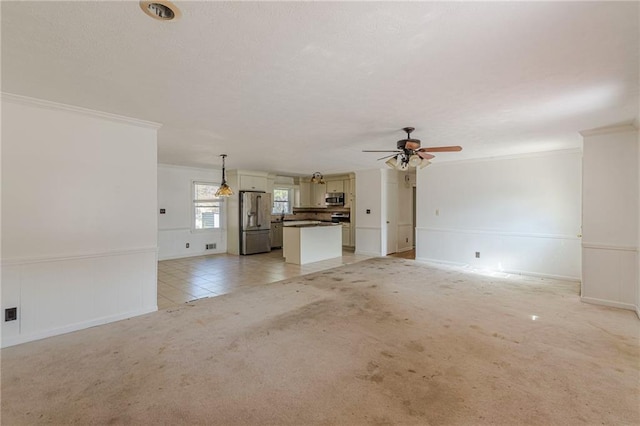 unfurnished living room featuring crown molding, light colored carpet, and ceiling fan