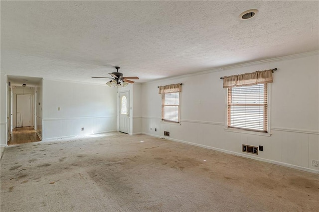 unfurnished room with light carpet, ceiling fan, crown molding, and a textured ceiling