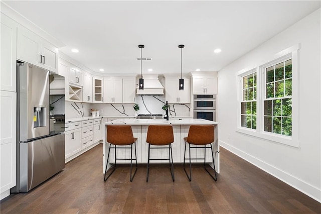 kitchen featuring premium range hood, appliances with stainless steel finishes, dark hardwood / wood-style floors, and white cabinets