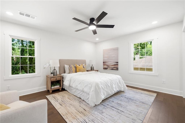 bedroom featuring ceiling fan, dark hardwood / wood-style floors, and multiple windows