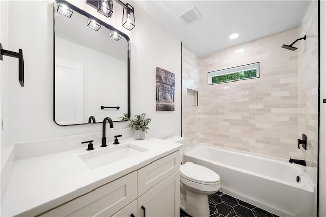 full bathroom with tile patterned floors, vanity, tiled shower / bath, and toilet