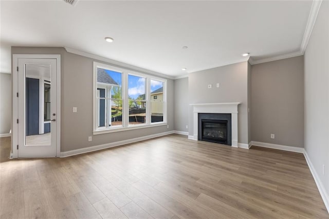 unfurnished living room featuring crown molding, wood finished floors, baseboards, and a glass covered fireplace