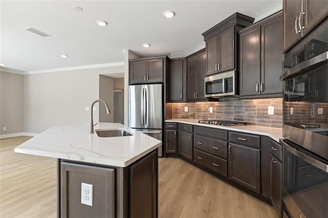 kitchen with a sink, stainless steel appliances, visible vents, decorative backsplash, and light wood-style floors