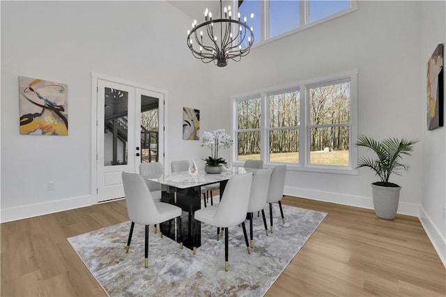 dining space with a high ceiling, hardwood / wood-style floors, and a chandelier