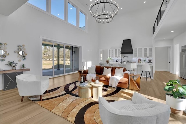 living room featuring a high ceiling, light wood-type flooring, and an inviting chandelier