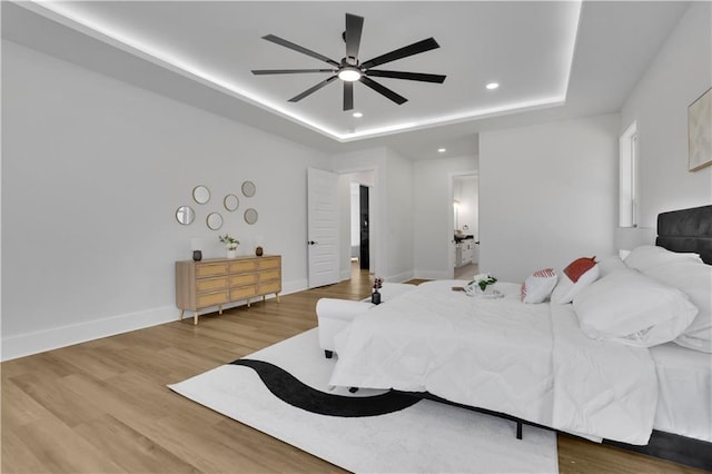 bedroom with ceiling fan, a raised ceiling, and hardwood / wood-style flooring