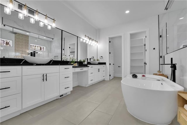 bathroom featuring vanity, decorative backsplash, tile patterned floors, and a tub