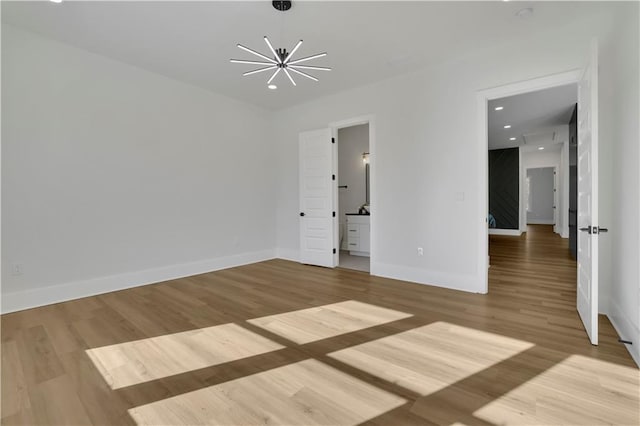 unfurnished room featuring a chandelier and hardwood / wood-style floors