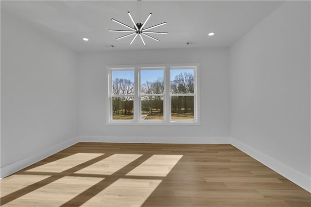 unfurnished room featuring an inviting chandelier and light hardwood / wood-style flooring