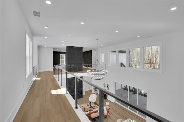 corridor with a healthy amount of sunlight, hardwood / wood-style flooring, and a notable chandelier