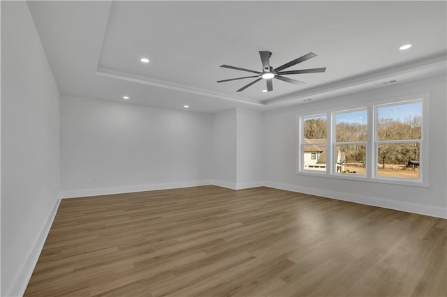 unfurnished room with ceiling fan, wood-type flooring, and a tray ceiling