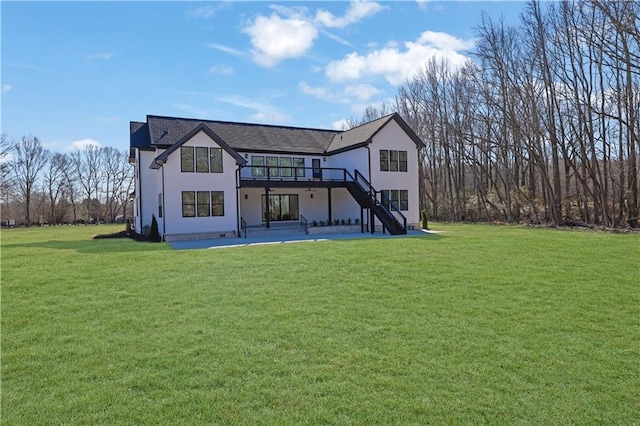 rear view of property featuring a lawn, a wooden deck, and a patio