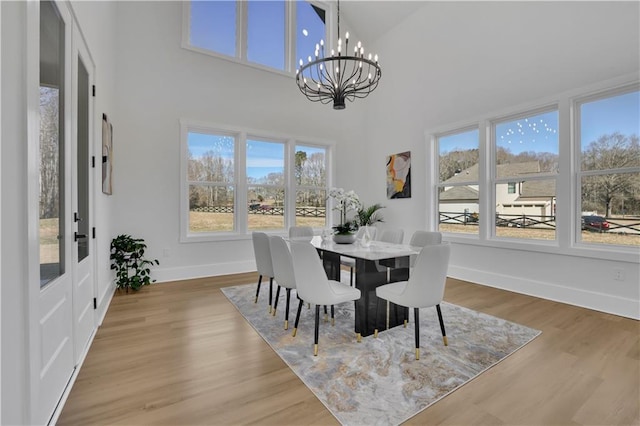 dining room featuring high vaulted ceiling, wood-type flooring, and a chandelier